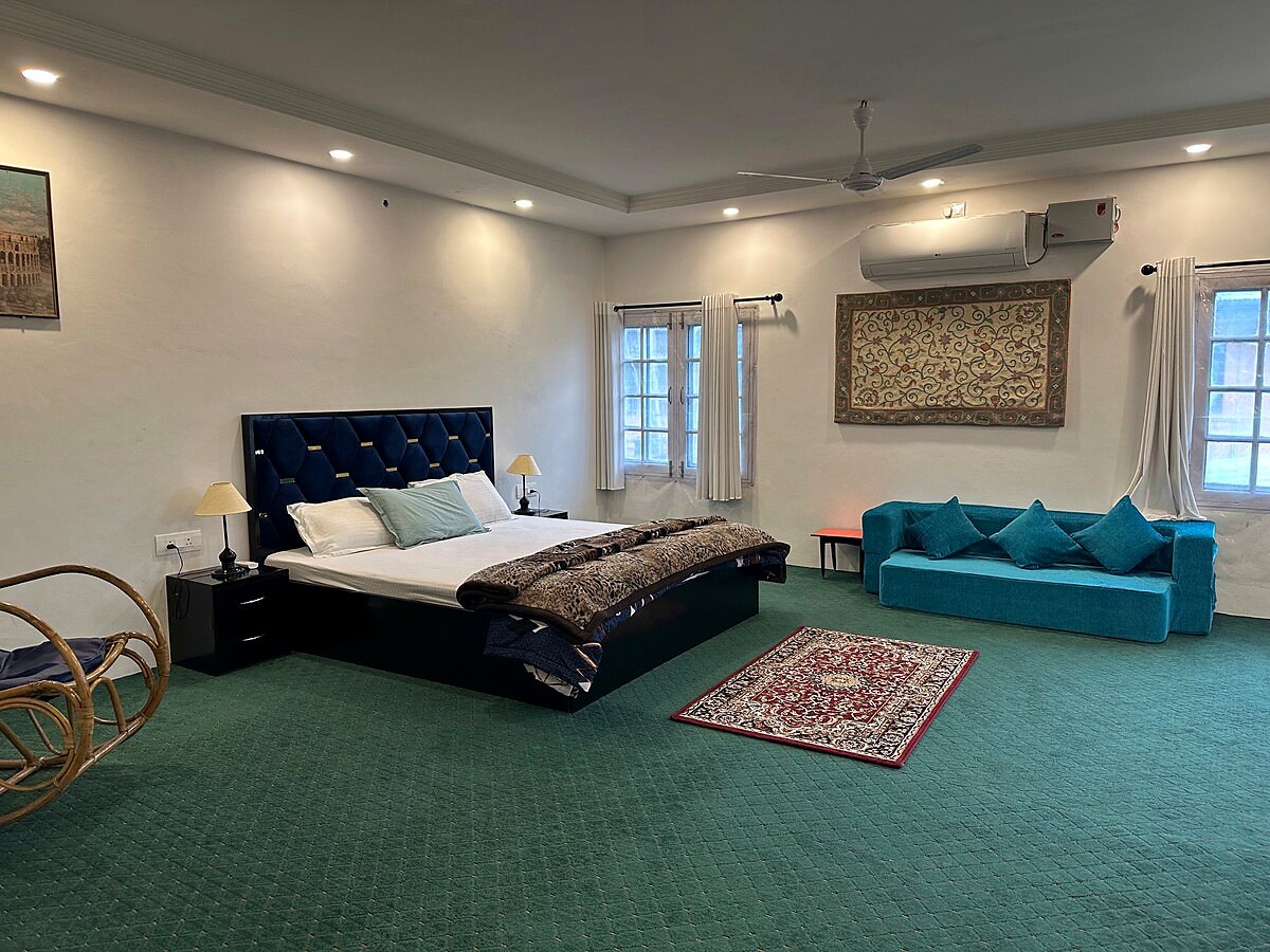 Bedroom one at Chinar House with bed, sofa seating, and wardrobe