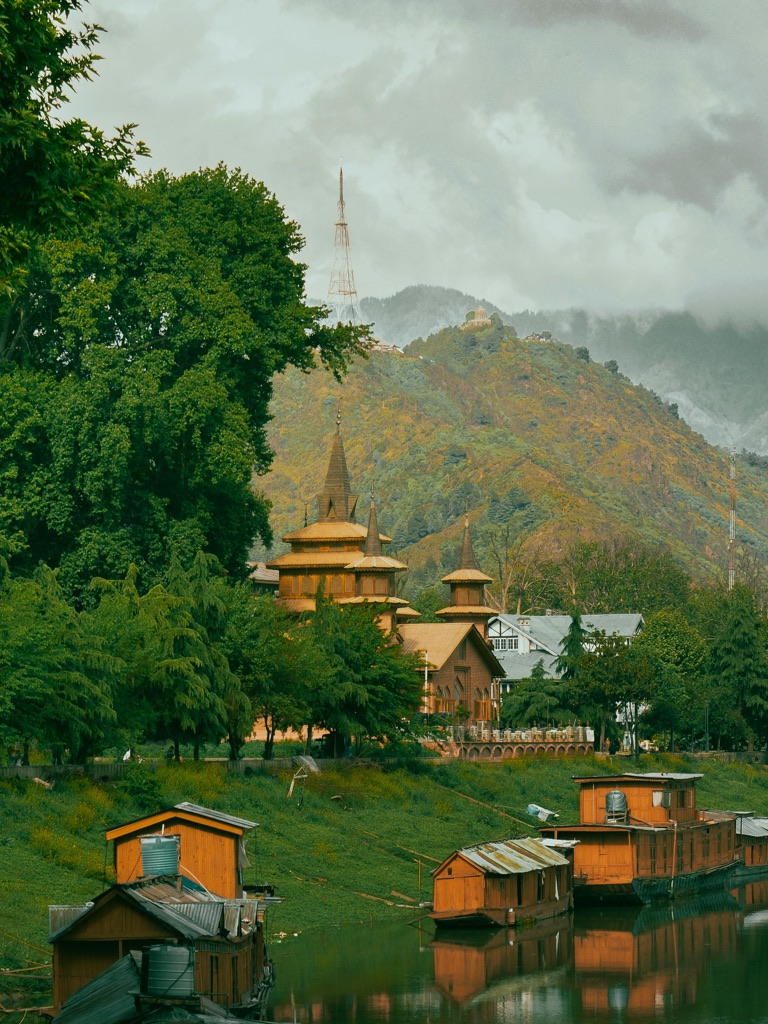 A calm Srinagar lakeside scene with boats and mountains